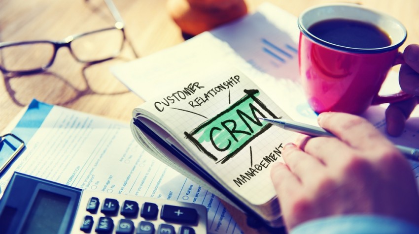 Person planning customer relationship strategy in a notebook labelled CRM, researching the best crm in malaysia for their business.